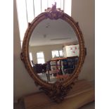 Large ornate oval gold reproduction mirror, 148cm tall.