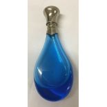 A teal blue perfume bottle with white metal lid.