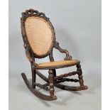 A 19c Black Forest naturalistically carved rocking chair with caned back panel and circular seat.