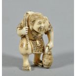 A 19c ivory netsuke carved as a fisherman carrying a large fish on his back and with a basket in his