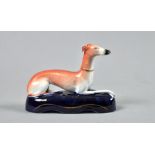 A 19c Staffordshire pen holder in the form of a recumbent greyhound on an oval blue glazed base, 6"