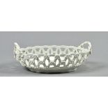 A white glazed undecorated oval Worcester basket, the twisted rope handles with floral terminals,