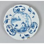 A Delft blue and white plate, the border with cottages in reserves interspersed with leaves, the