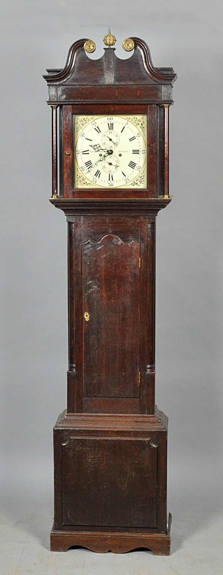 An early 19c eight day longcase clock with a 12" square brass dial having florally painted corners