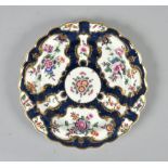A Worcester plate with shaped border painted with flowers within elaborate gilt reserves on a