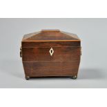 A late Georgian rosewood two compartment tea caddy of sarcophagus form with a facet domed hinged