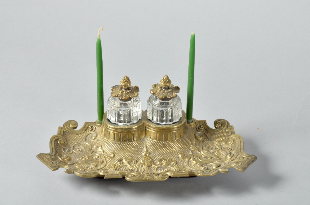 A Victorian brass two bottle inkstand, rococo cast and having two clear glass moulded bottles (one