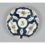 A Worcester plate with shaped border painted with flowers in simple reserves on a scale blue ground,