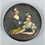 A 19c black lacquered papier mache circular box and cover, painted with a lady seated at a table