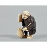 A 19c wood and ivory netsuke carved as a figure with a lantern and a book in the right hand, base