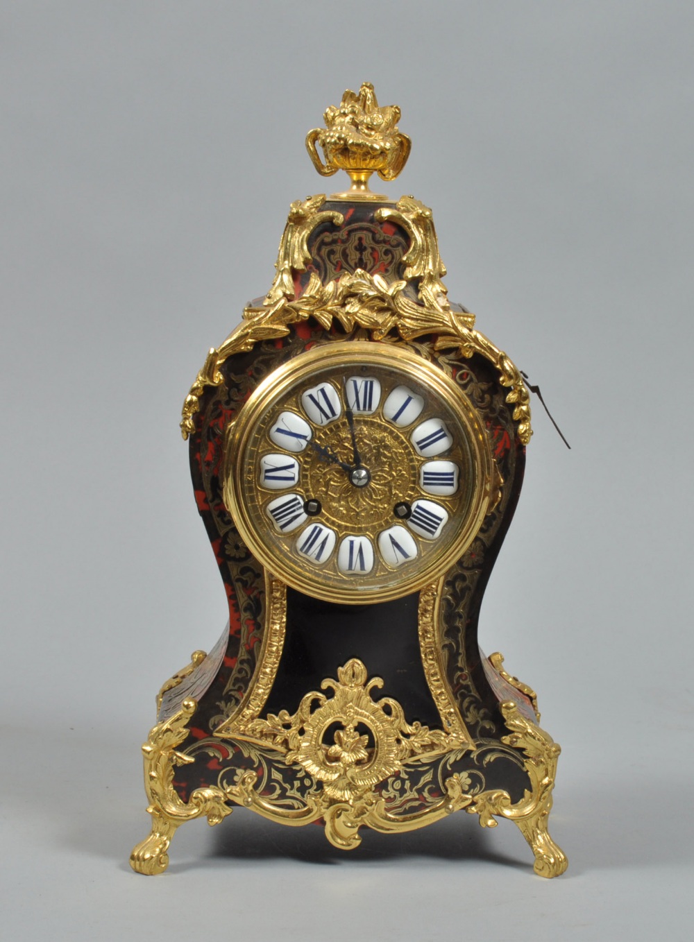 A late 19c French mantel clock in waisted red boullework case with gilded brass feet and mounts