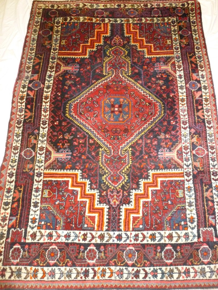 An Eastern hand knotted wool rug with geometric decoration on blue and red ground 72" x 47"