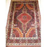 An Eastern hand knotted wool rug with geometric decoration on blue and red ground 72" x 47"