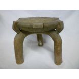 An old African tribal carved wood three legged stool with circular seat