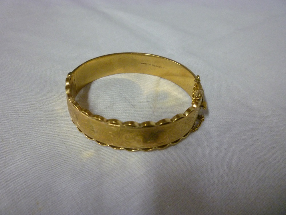 A 9ct gold oval bangle with engraved and pierced decoration