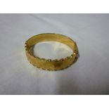 A 9ct gold oval bangle with engraved and pierced decoration