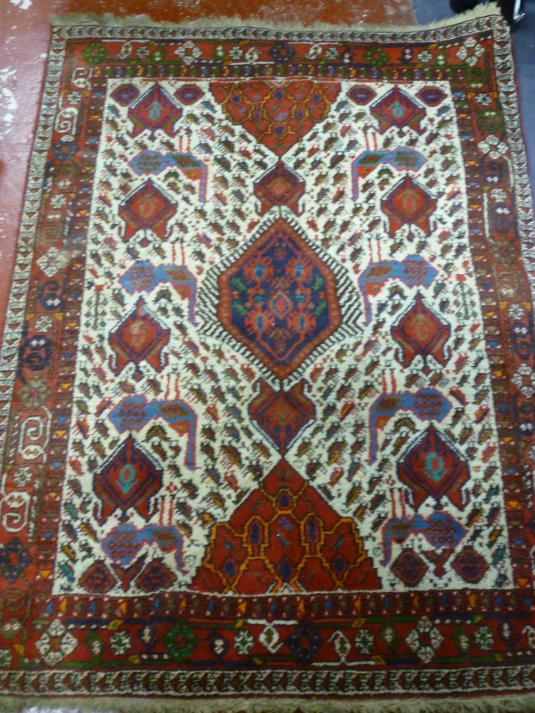 An Eastern hand knotted wool rug with bird, animal and geometric decoration on red and cream
