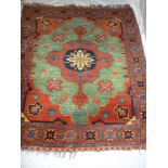 An Eastern hand knotted wool rug with geometric decoration on green, red and blue ground, 73" x 62"