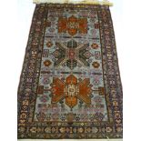 An old Eastern hand knotted wool rug with geometric decoration on red and blue ground 79" x 48"