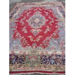 A large Eastern-style rectangular carpet with floral decoration on red and blue ground 12ft x 10ft