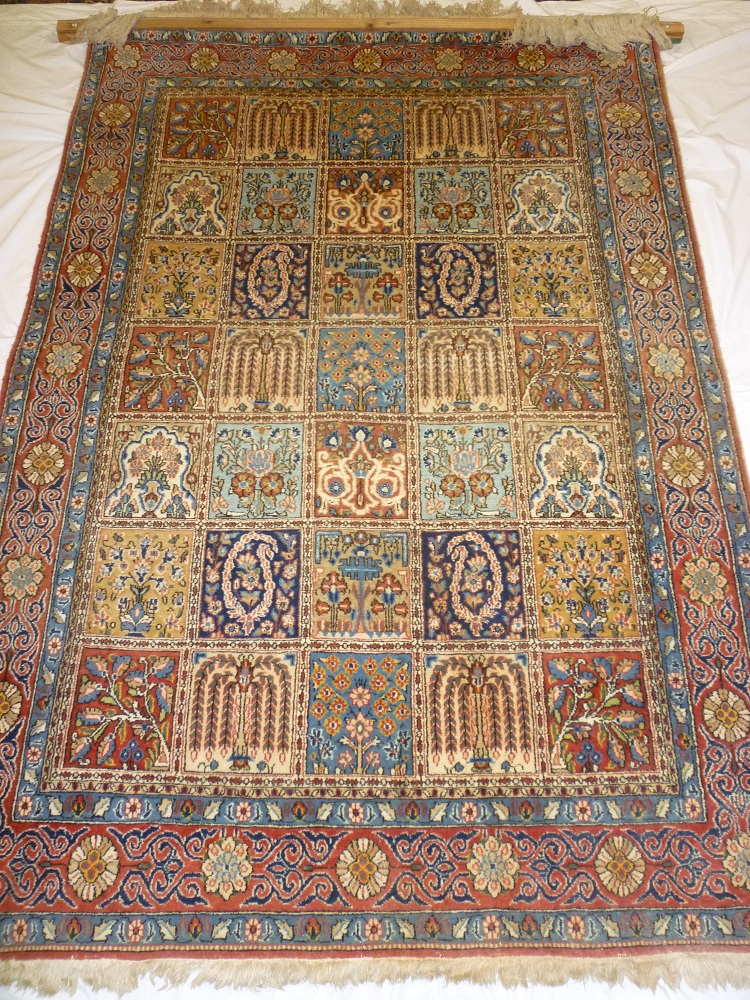 A good quality old Eastern hand knotted wool rug with central rectangular panels of flowers and