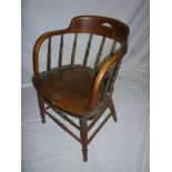 An old stained wood Captain-style armchair with spindle back and shaped seat on turned tapered legs