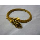 An unusual 14ct gold bangle in the form of a snake with enamelled head inset with diamonds and