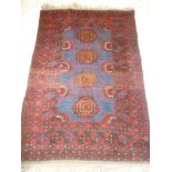 An Eastern hand knotted wool rug with geometric decoration on red and blue ground 60" x 41"