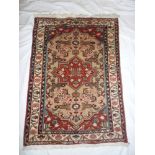 A small Eastern hand knotted wool rug with geometric decoration on red and cream ground 36" x 26"