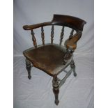 An old elm Captain-style carver armchair with spindle back and shaped seat on turned tapered legs