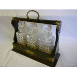 An unusual three-bottle tantalus containing three cut glass square decanters and stoppers (slight
