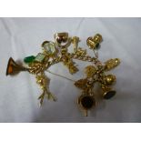 A 9ct gold charm bracelet supporting numerous gold and gilt charms including 19th century gilt fob
