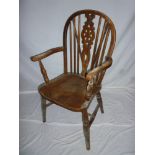 An old elm and beech wheel back carver armchair with shaped seat on turned tapered legs