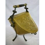 An ornate brass twin-section oval coal bucket with raised scroll decoration, turned wood handle