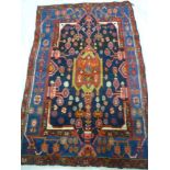 An Eastern hand knotted wool rug with geometric floral decoration on red and blue ground 68" x 43"