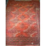 An old Eastern hand knotted Bokhara-style wool rug with geometric decoration on red ground 86" x 62"