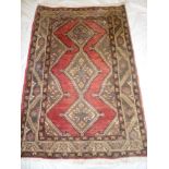 An Eastern hand knotted wool rug with geometric decoration on red and brown ground 55" x 39"
