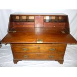 An early 19th century mahogany bureau with numerous drawers , pigeon holes and a cupboard enclosed