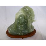 A Chinese jadeite/soapstone carved figure of a seated Buddha amongst foliage