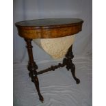 A mid-Victorian inlaid walnut oval work table with fitted interior and fabric compartments on turned