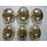 Six electroplated matching graduated oval domed food covers with reeded edges and scroll handles