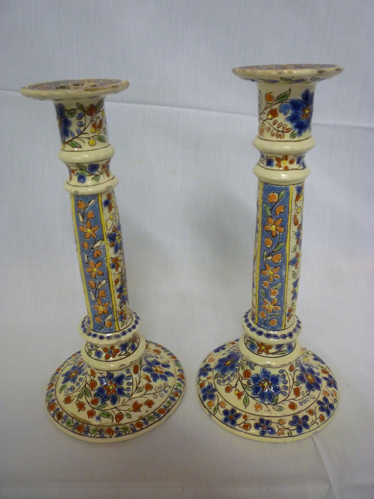 A pair of Continental pottery candlesticks with floral decoration on circular spreading bases
