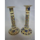 A pair of Continental pottery candlesticks with floral decoration on circular spreading bases