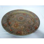 An unusual Eastern copper circular charger decorated in relief with red and turquoise composition