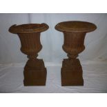 A pair of Victorian cast iron classical-shaped garden pedestal urns with fluted decoration and
