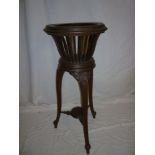 An Edwardian stained beech circular jardiniere stand with pierced circular body on three scroll legs