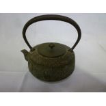 An old Chinese iron circular teapot with loop handle and brass lid