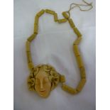 An unusual Art Deco carved pendant necklace in the form of a stylised female face with floral head