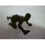 A bronze figure of a crawling African male