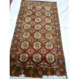 An old Eastern hand knotted Bokhara-style wool rug with medallion decoration on red ground 79" x 41"